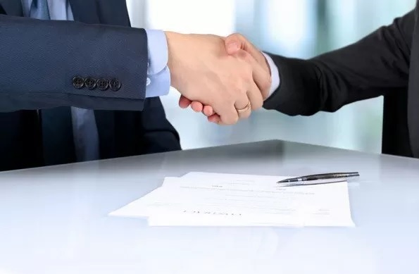 Due persone si stringono la mano dopo aver firmato il contratto